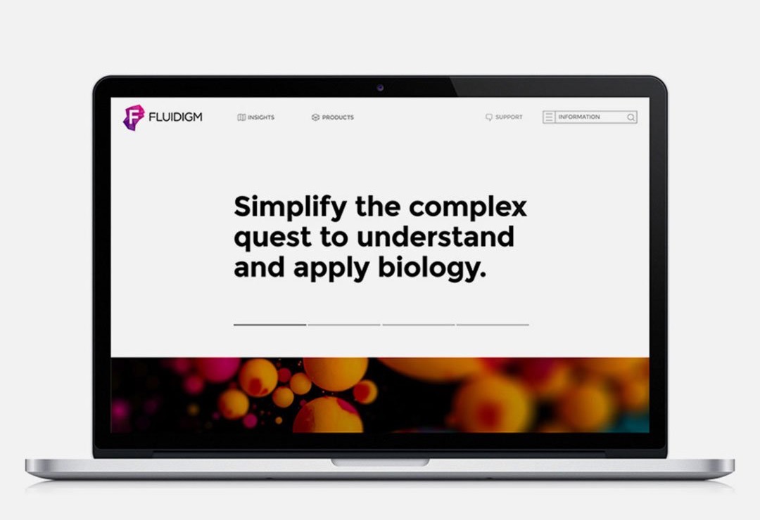The Fluidigm website home page on a laptop, headlined “Simplify the complex quest to understand and apply biology” above a band of magnified cells